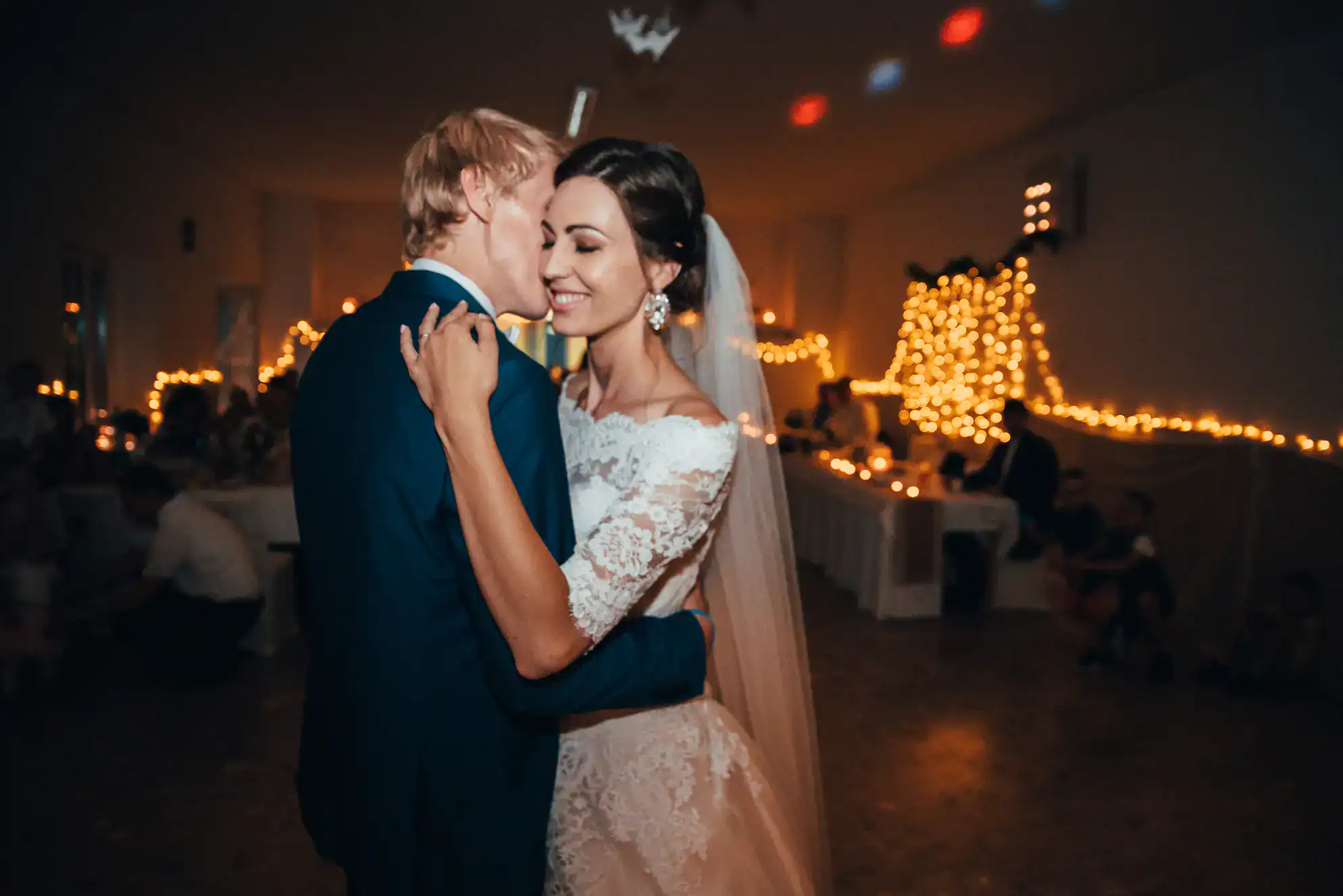 A bride and groom share a joyful first dance at their wedding reception, surrounded by warm fairy lights&mdash;a magical moment made even more special by ballroom dance lessons in Suffolk County, NY.